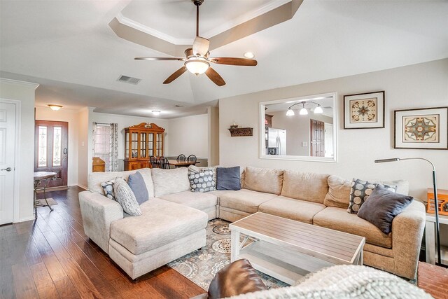 living room with a tray ceiling, crown molding, dark hardwood / wood-style flooring, and ceiling fan