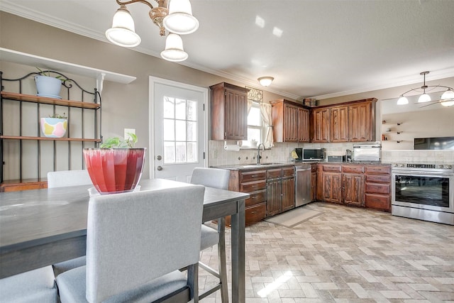 kitchen with backsplash, sink, ornamental molding, decorative light fixtures, and stainless steel appliances