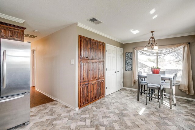 dining room with a chandelier, a textured ceiling, and ornamental molding