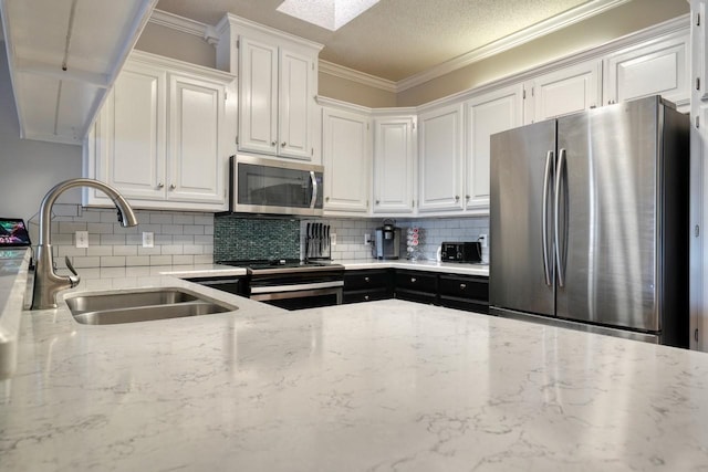 kitchen featuring light stone countertops, sink, stainless steel appliances, white cabinets, and ornamental molding