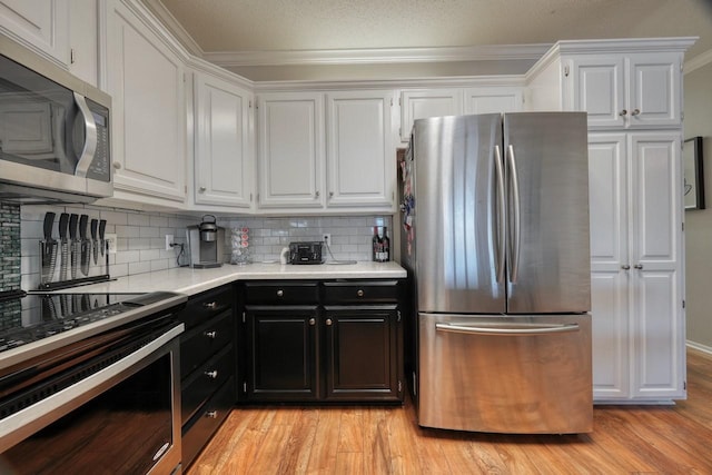 kitchen featuring decorative backsplash, white cabinets, light hardwood / wood-style floors, and appliances with stainless steel finishes