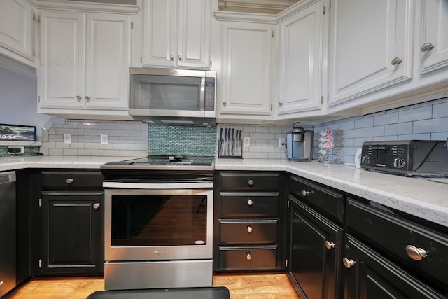 kitchen featuring decorative backsplash, light wood-type flooring, light stone counters, stainless steel appliances, and white cabinets