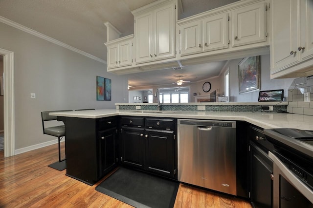 kitchen featuring white cabinetry, dishwasher, sink, kitchen peninsula, and a breakfast bar area