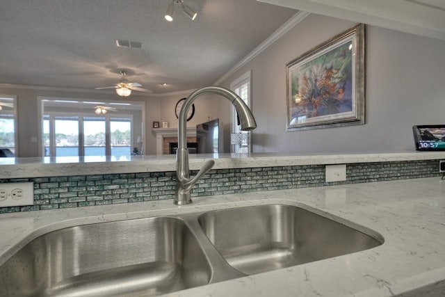 details featuring ceiling fan, light stone counters, and sink