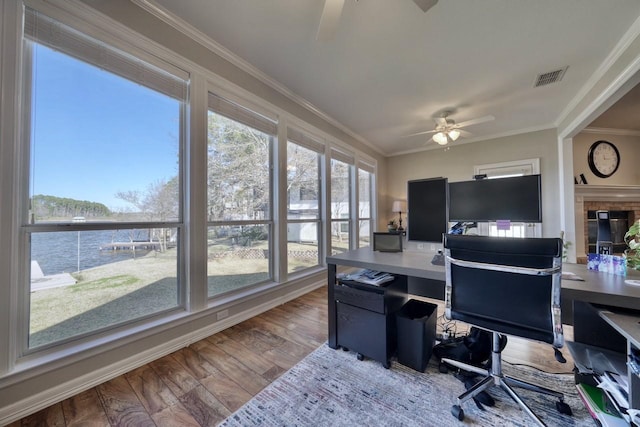 office area with ceiling fan, a water view, wood-type flooring, and ornamental molding