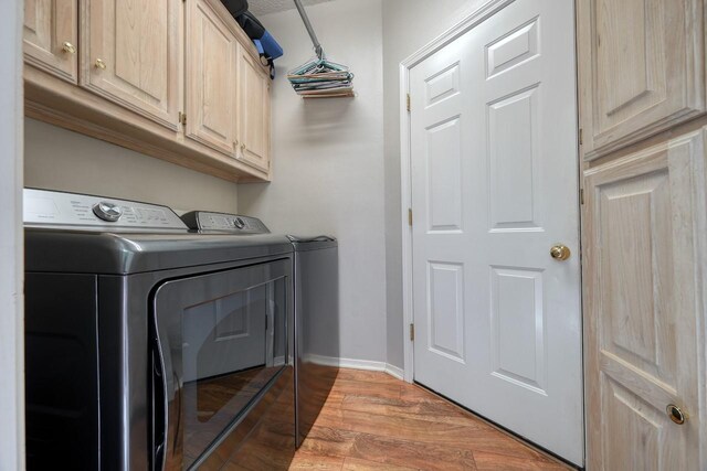 clothes washing area featuring cabinets, hardwood / wood-style floors, and separate washer and dryer