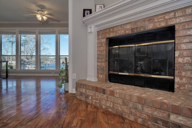 interior details featuring a fireplace, wood-type flooring, a water view, and crown molding