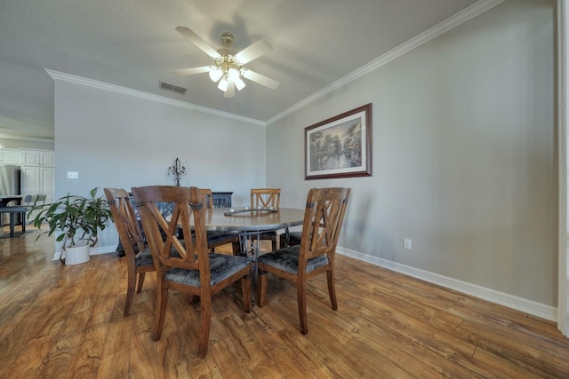 dining space with a textured ceiling, hardwood / wood-style flooring, ceiling fan, and crown molding