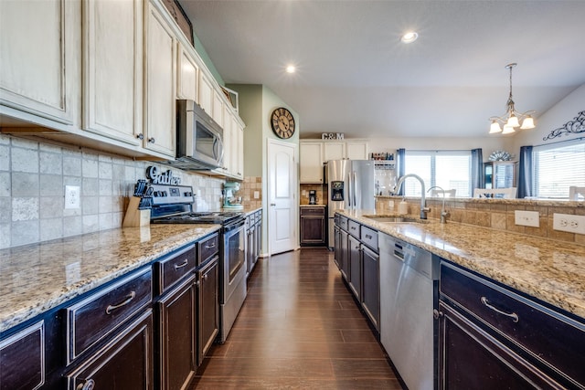 kitchen featuring a chandelier, light stone counters, sink, and stainless steel appliances