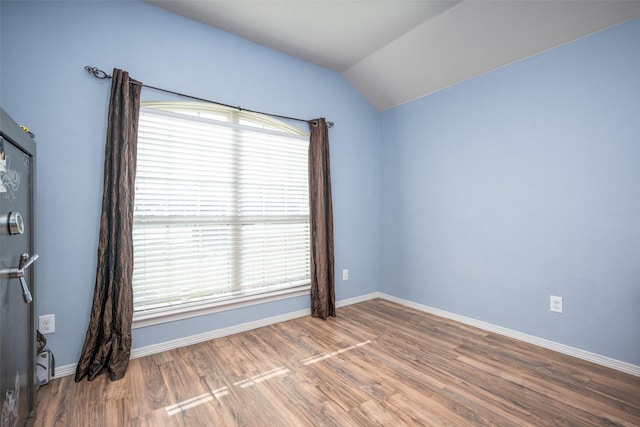 spare room with lofted ceiling and hardwood / wood-style flooring