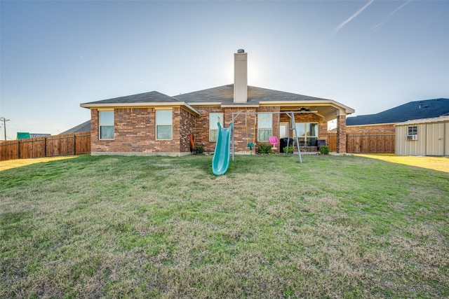 rear view of house featuring a yard and a shed