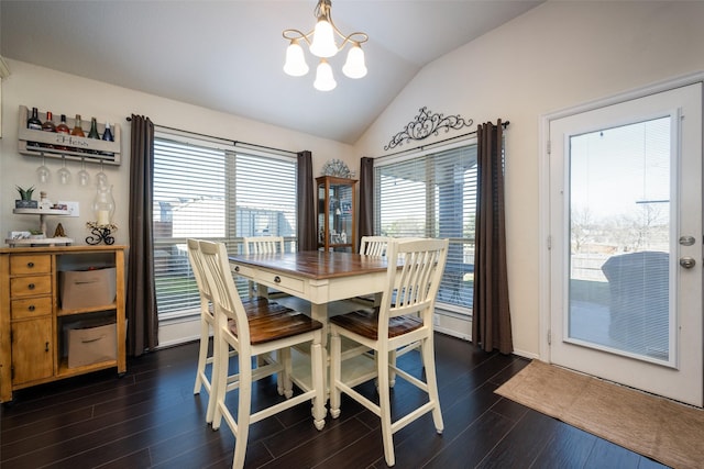 dining area with a healthy amount of sunlight, dark hardwood / wood-style floors, lofted ceiling, and an inviting chandelier