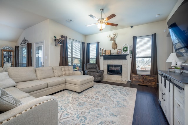 living room featuring a tiled fireplace, ceiling fan, dark wood-type flooring, and lofted ceiling