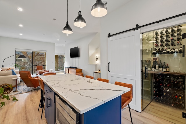 kitchen with a kitchen bar, pendant lighting, a barn door, and blue cabinetry