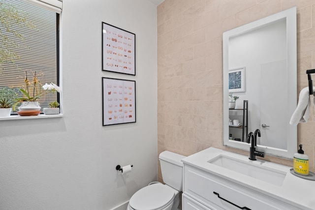 bathroom featuring vanity, toilet, and tile walls