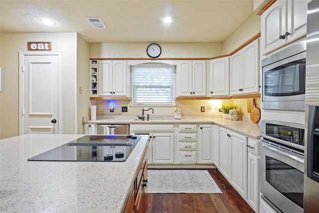 kitchen featuring light stone countertops, stainless steel appliances, sink, white cabinets, and dark hardwood / wood-style floors