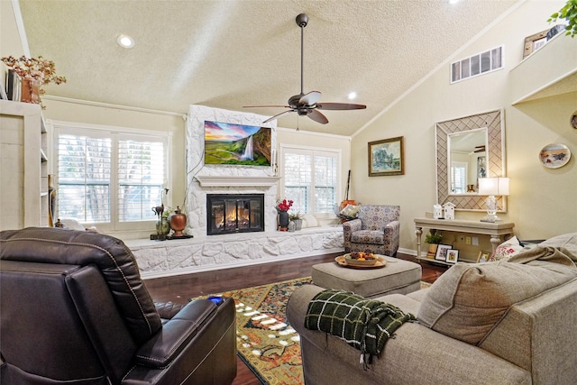 living room with a wealth of natural light, ceiling fan, a textured ceiling, vaulted ceiling, and hardwood / wood-style flooring