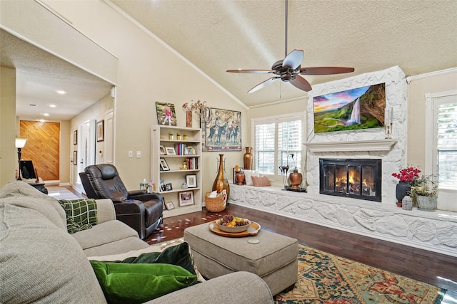 living room featuring a healthy amount of sunlight, a premium fireplace, wood walls, lofted ceiling, and a textured ceiling