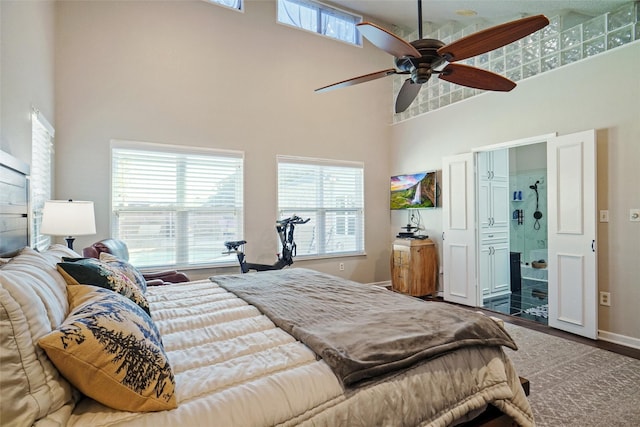 bedroom with ceiling fan, hardwood / wood-style floors, and a towering ceiling