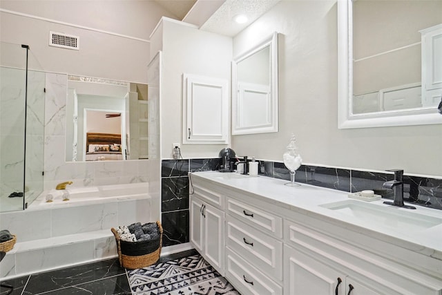 bathroom featuring a relaxing tiled tub and vanity