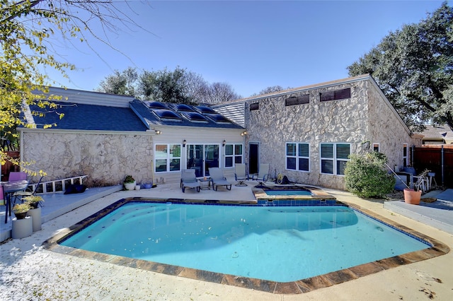 rear view of house featuring a pool with hot tub and a patio