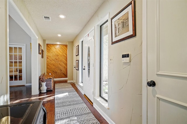 entryway featuring dark hardwood / wood-style flooring, a textured ceiling, and wood walls