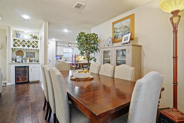 dining area featuring a textured ceiling, wine cooler, bar, and dark wood-type flooring