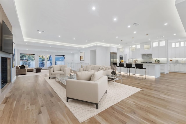 living room featuring a tray ceiling and light hardwood / wood-style flooring