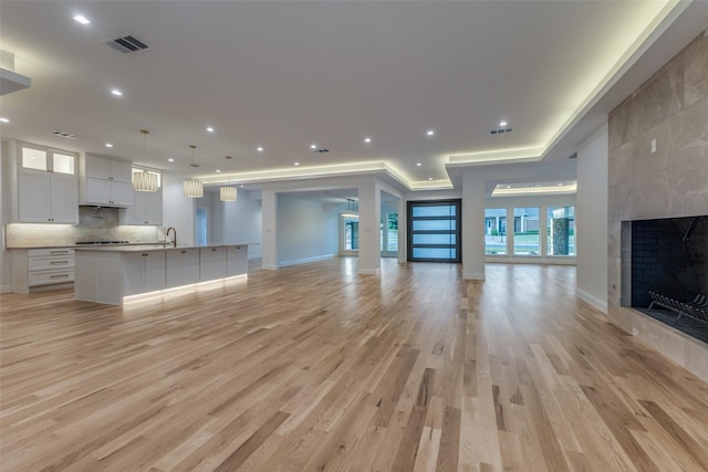 unfurnished living room featuring a fireplace, light hardwood / wood-style floors, and sink