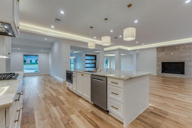 kitchen with a kitchen island with sink, white cabinets, stainless steel appliances, and light stone counters