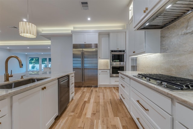 kitchen with light stone countertops, tasteful backsplash, stainless steel appliances, sink, and white cabinets