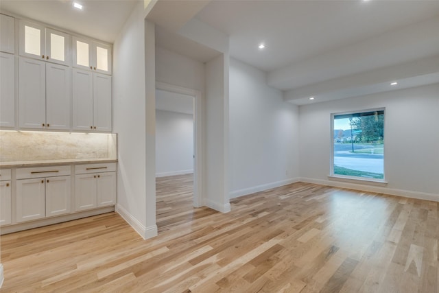 interior space featuring white cabinets, backsplash, and light hardwood / wood-style flooring