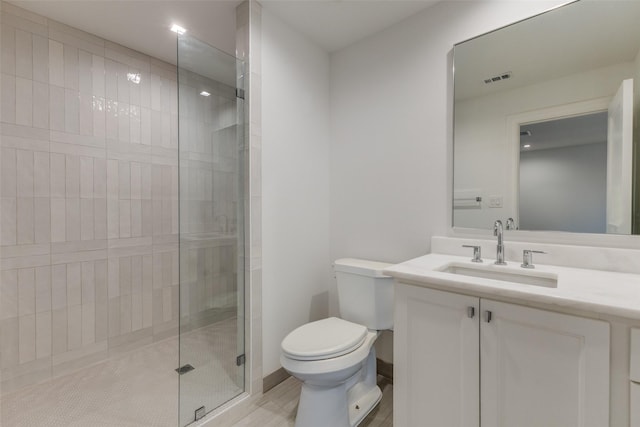 bathroom featuring vanity, a shower with shower door, and toilet