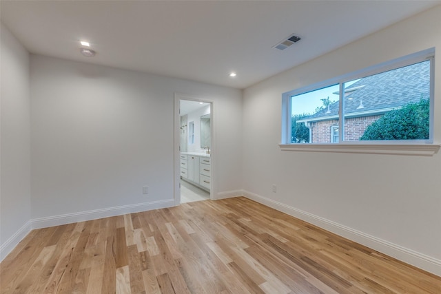 unfurnished bedroom with light hardwood / wood-style flooring and ensuite bath