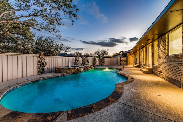 pool at dusk with an in ground hot tub and a patio