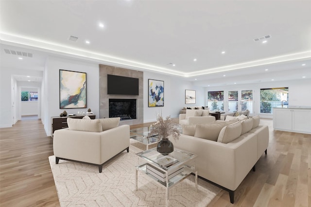 living room featuring a tile fireplace and light hardwood / wood-style floors