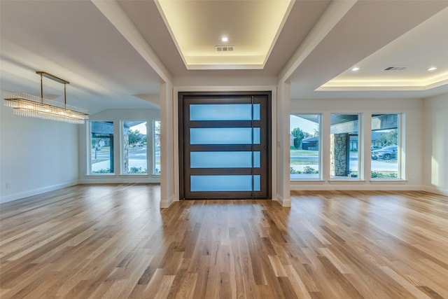 foyer with light hardwood / wood-style floors and a raised ceiling