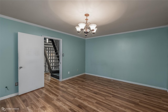 spare room featuring ornamental molding, dark wood-type flooring, and a chandelier