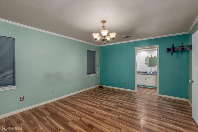 spare room featuring a notable chandelier, dark hardwood / wood-style floors, sink, and crown molding