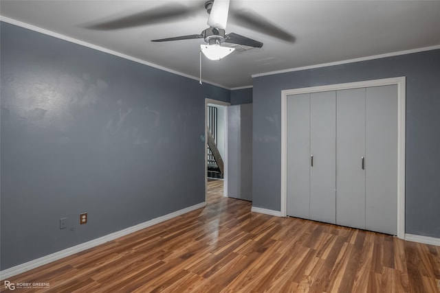 unfurnished bedroom with ceiling fan, a closet, dark wood-type flooring, and ornamental molding