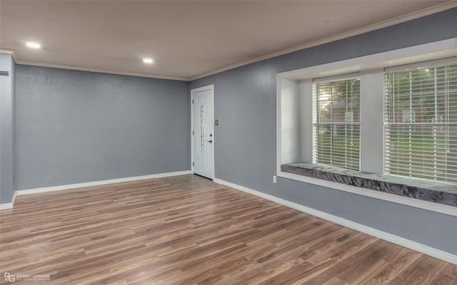 empty room with hardwood / wood-style flooring and crown molding