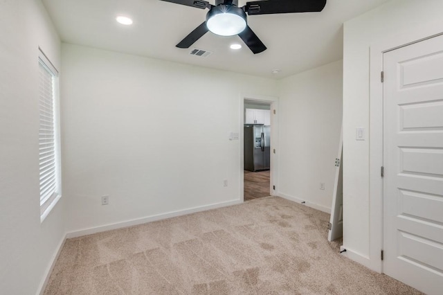 unfurnished bedroom featuring stainless steel refrigerator with ice dispenser, light carpet, and ceiling fan