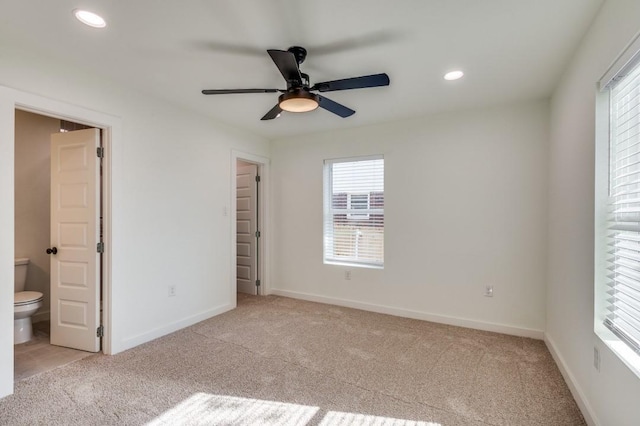 unfurnished bedroom with connected bathroom, light carpet, and ceiling fan