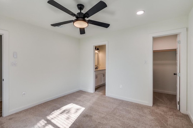 unfurnished bedroom featuring connected bathroom, a spacious closet, light carpet, and a closet