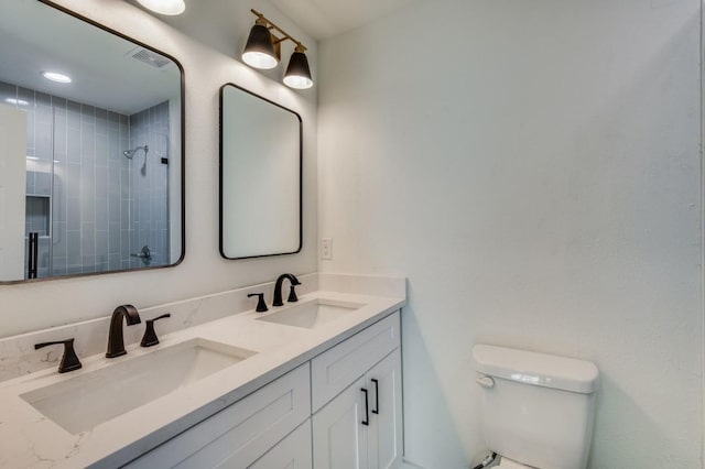 bathroom featuring tiled shower, vanity, and toilet