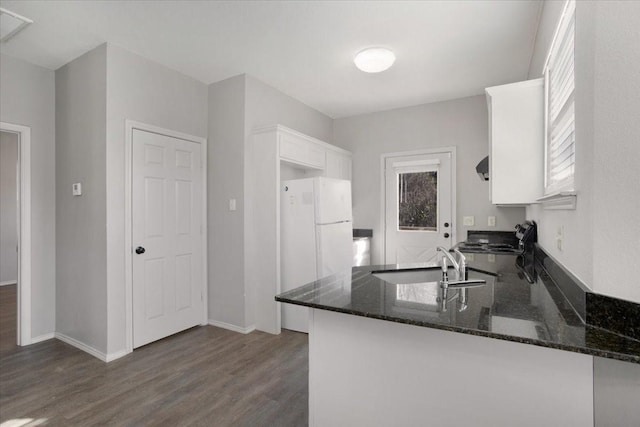 kitchen with stove, white refrigerator, sink, white cabinetry, and kitchen peninsula