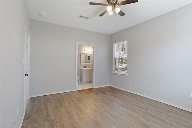 unfurnished bedroom featuring light wood-type flooring, ensuite bathroom, and ceiling fan