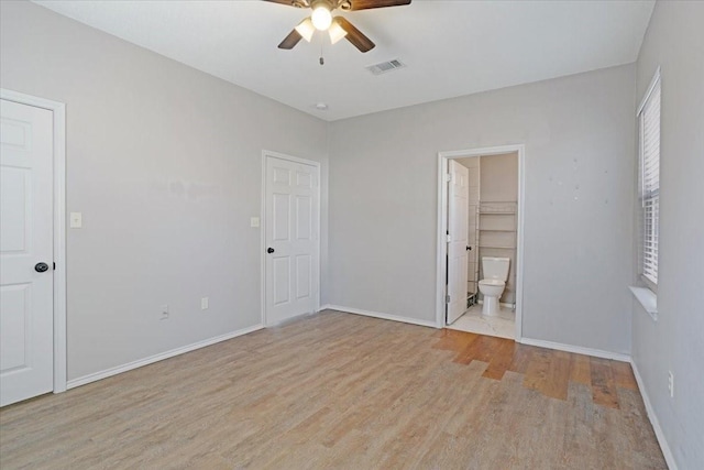 unfurnished bedroom with ensuite bath, ceiling fan, light hardwood / wood-style flooring, and a spacious closet