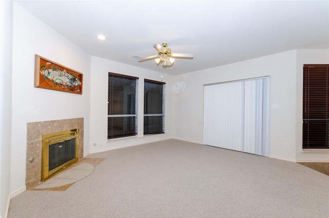 living room with a tiled fireplace, light carpet, and ceiling fan