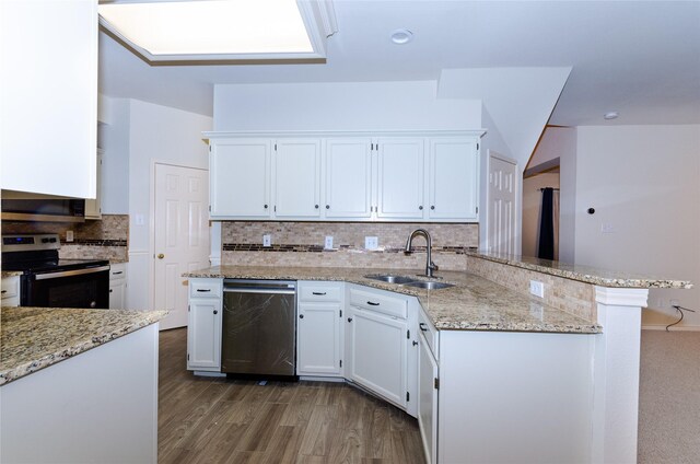 kitchen with kitchen peninsula, light stone countertops, stainless steel appliances, sink, and white cabinetry